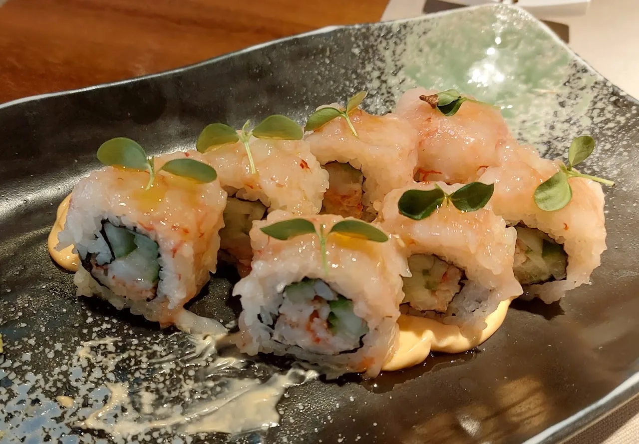 Sushi rolls topped with salmon and a drizzled sauce