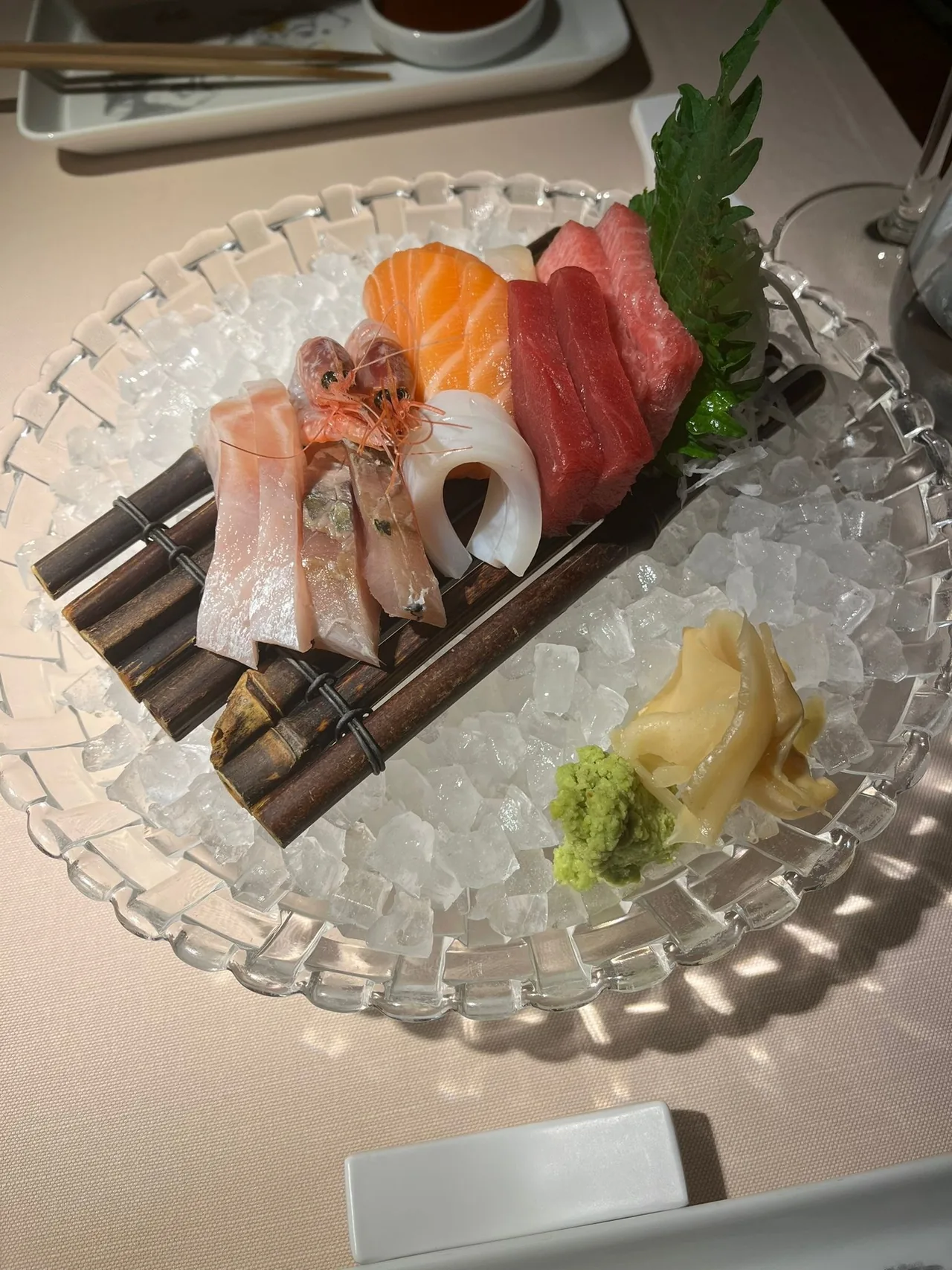 A sashimi platter on a glass dish with wasabi