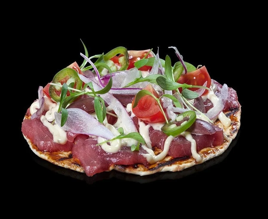A round crisp base topped with tuna, red onion and sprouts