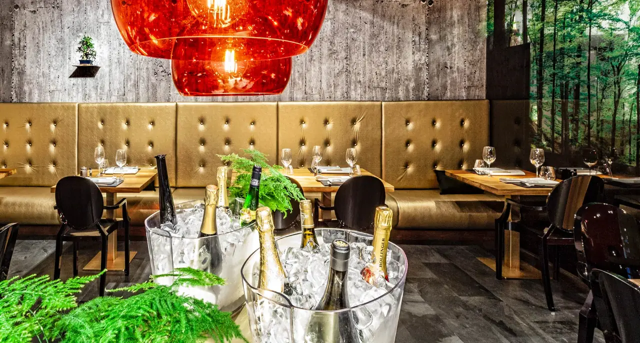 Dining room with gold tufted banquette seating and champagne bottles chilling in ice buckets