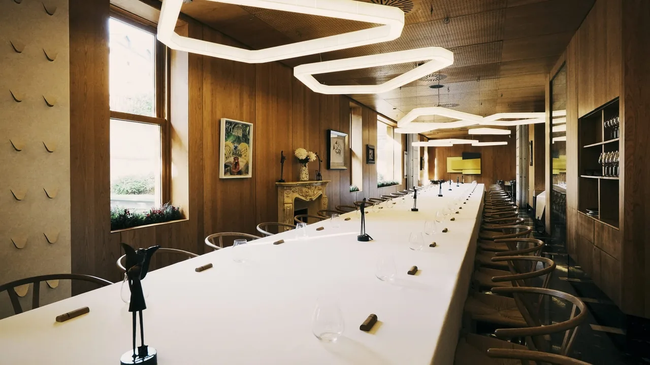A long white-clothed table under curved ceiling lights in a wood-panelled room