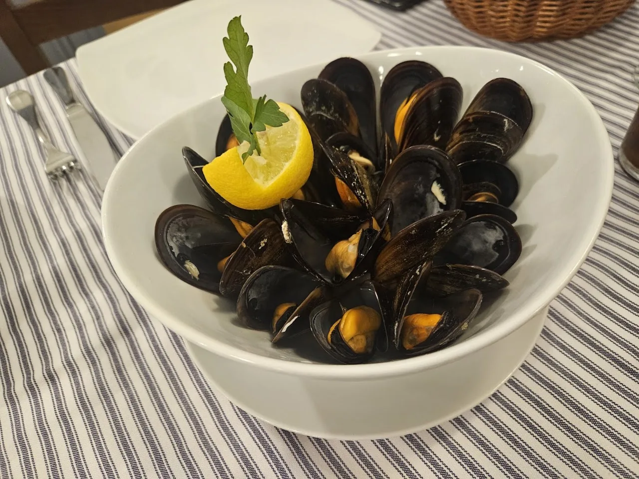 A bowl of steamed mussels with a lemon wedge