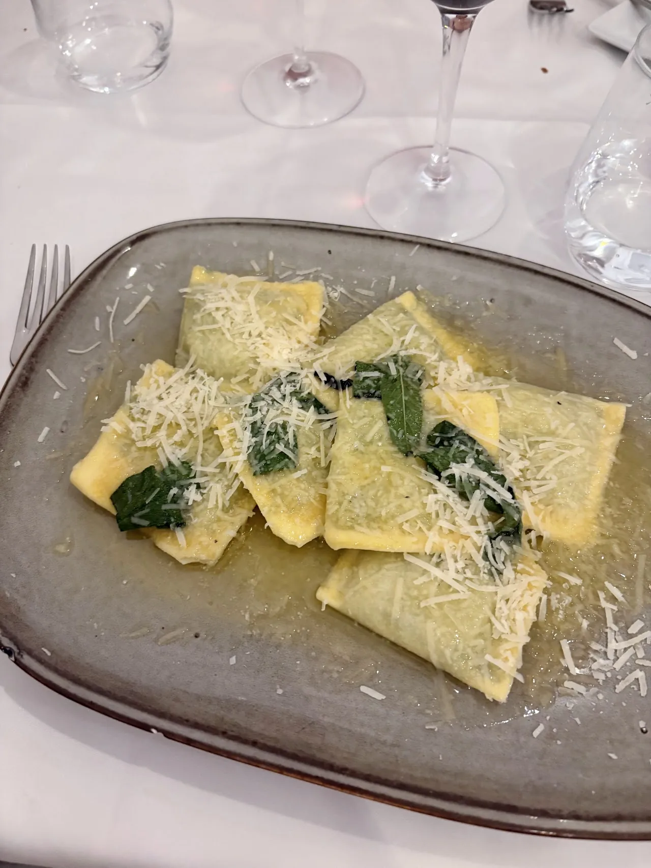 Sage butter ravioli with grated cheese on a plate