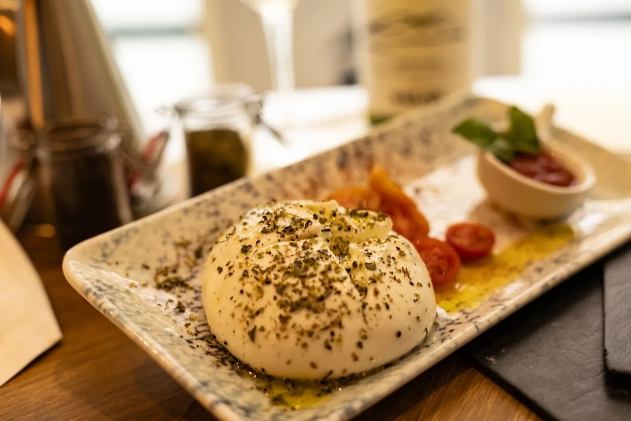 A ball of burrata with cherry tomatoes and olive oil on a platter