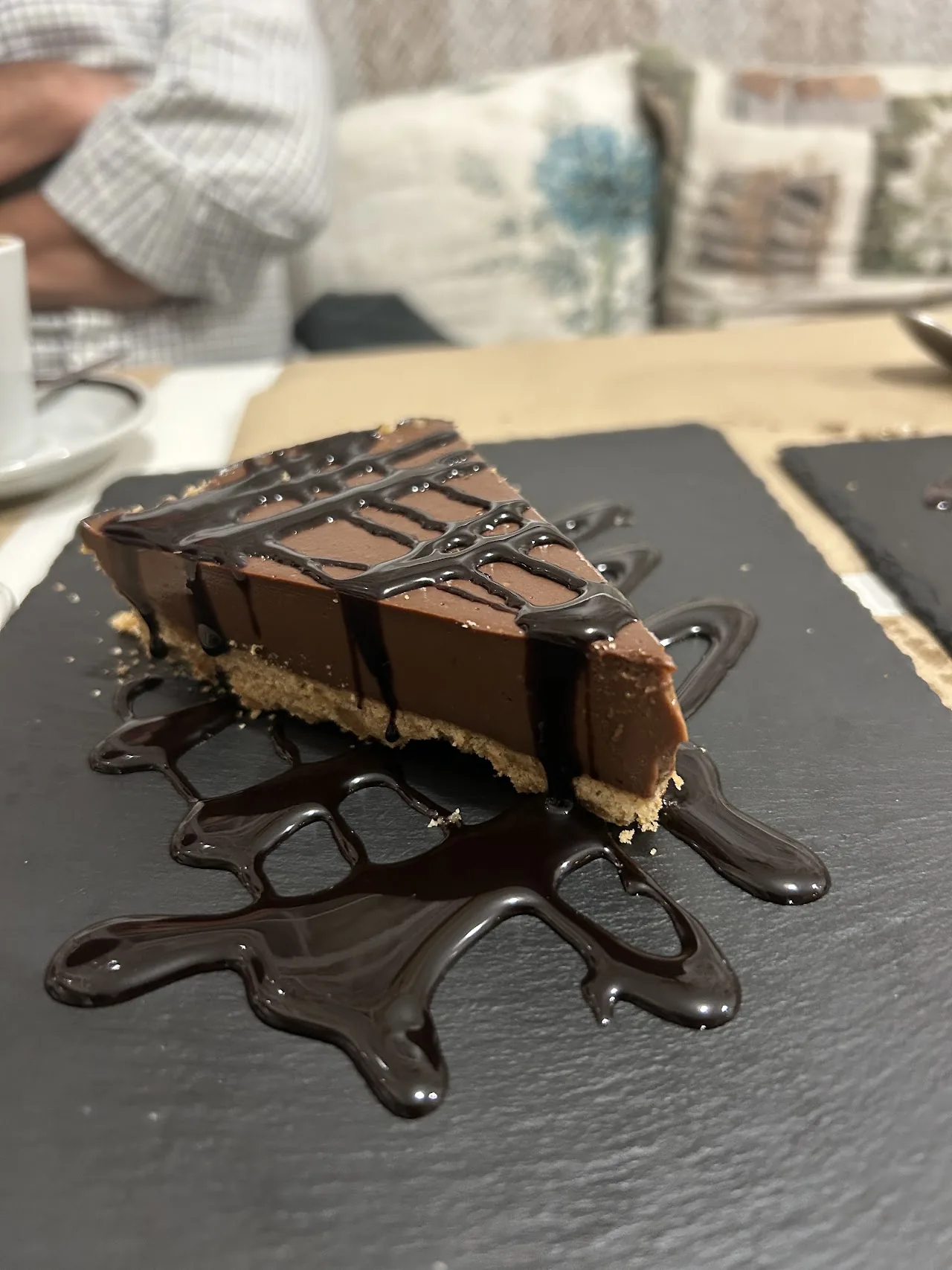 A slice of chocolate layer cake with chocolate drizzle