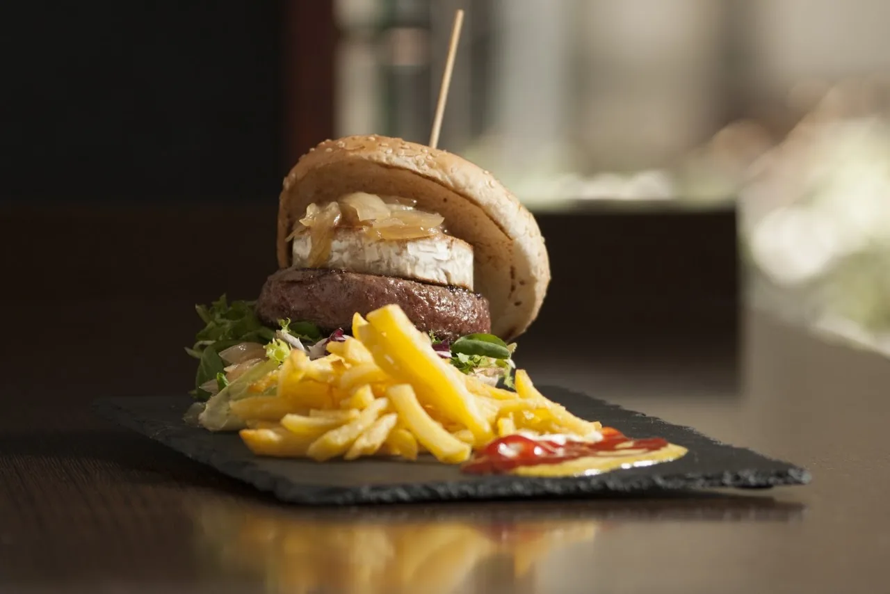 A burger with a fried egg and fries on a slate board