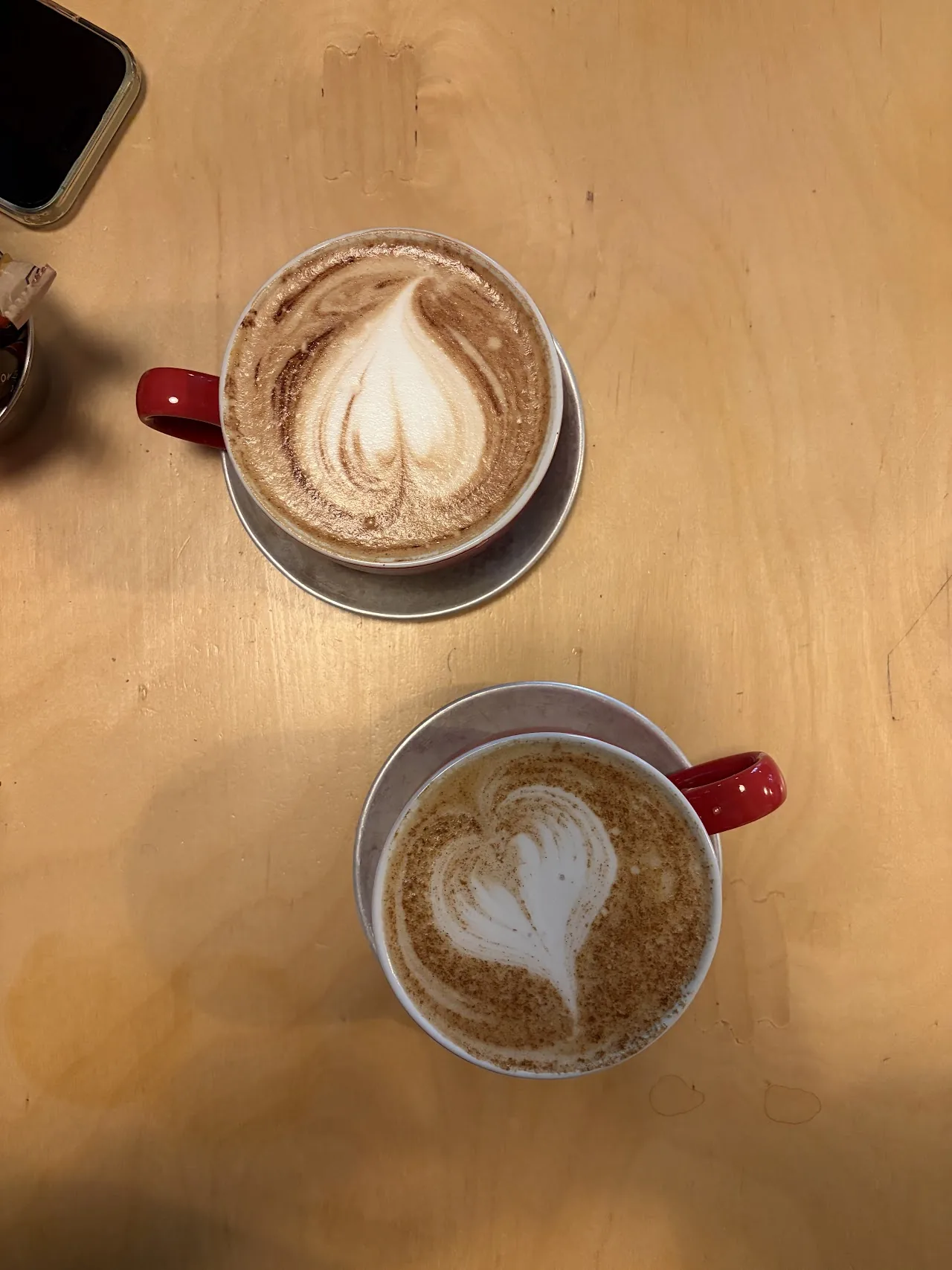 Two cappuccinos with latte art on a wooden table