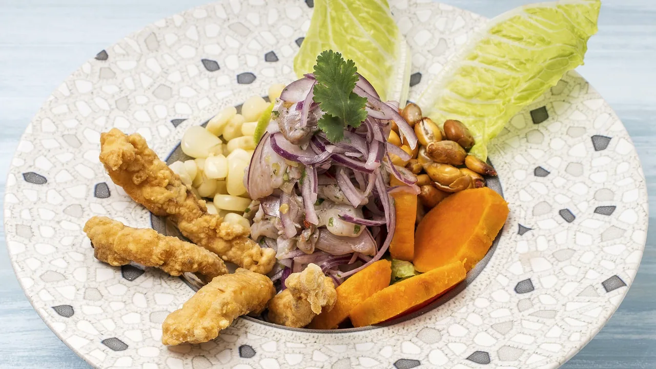 A patterned bowl of fried fish strips with red onion, sweet potato, corn kernels and lettuce