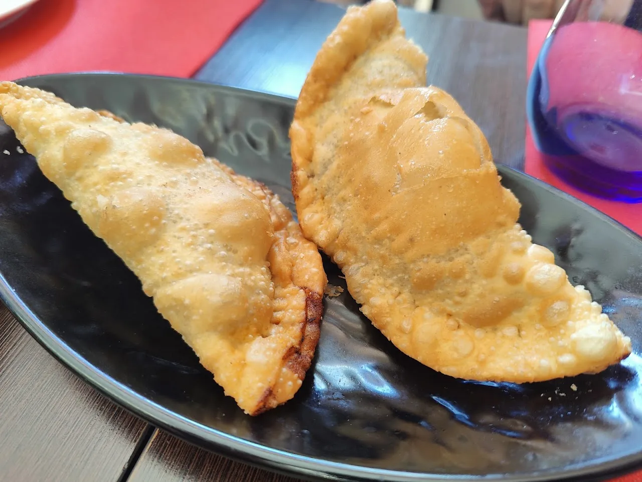 Two golden fried Cuban empanadas on a plate