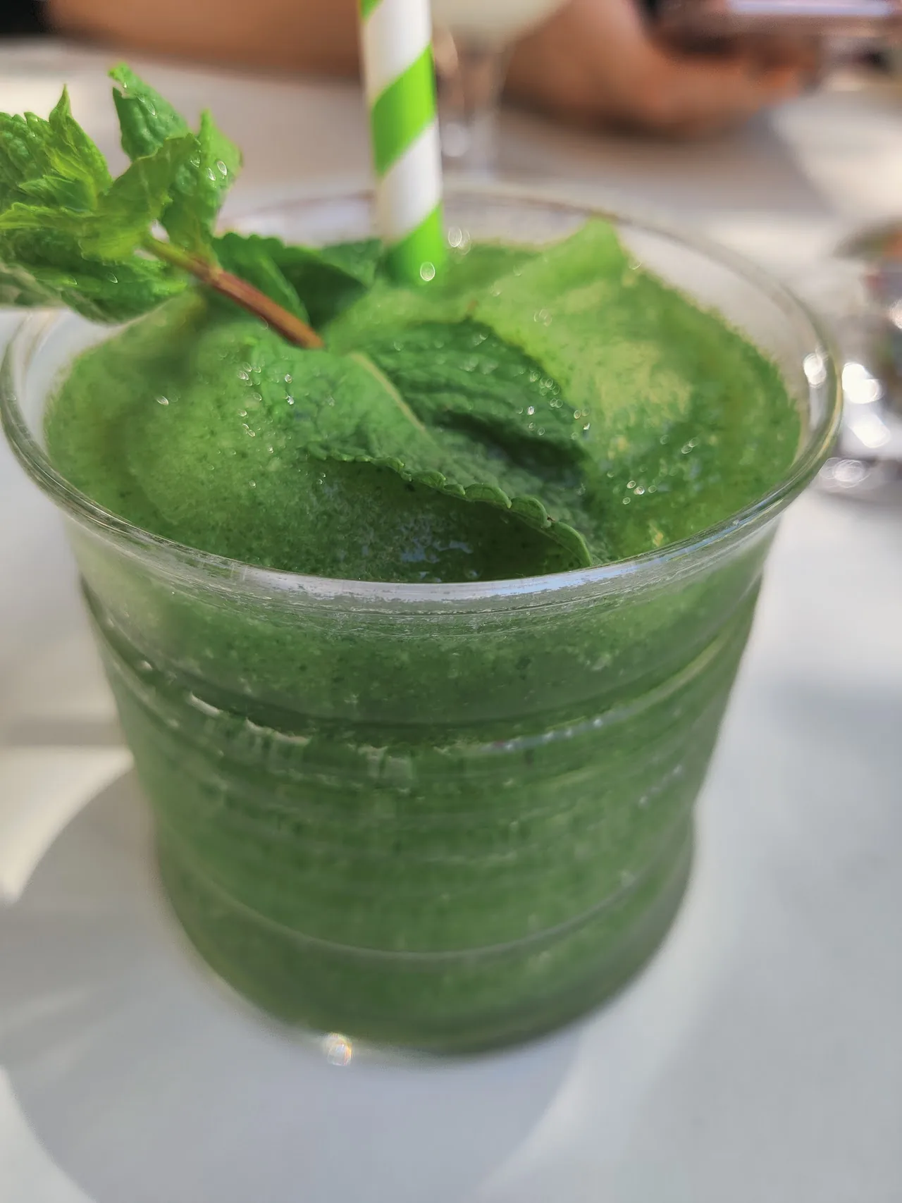 A green mojito cocktail garnished with mint