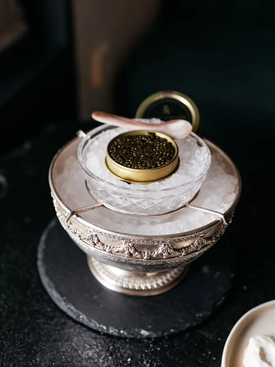 A tin of caviar on ice in a silver bowl