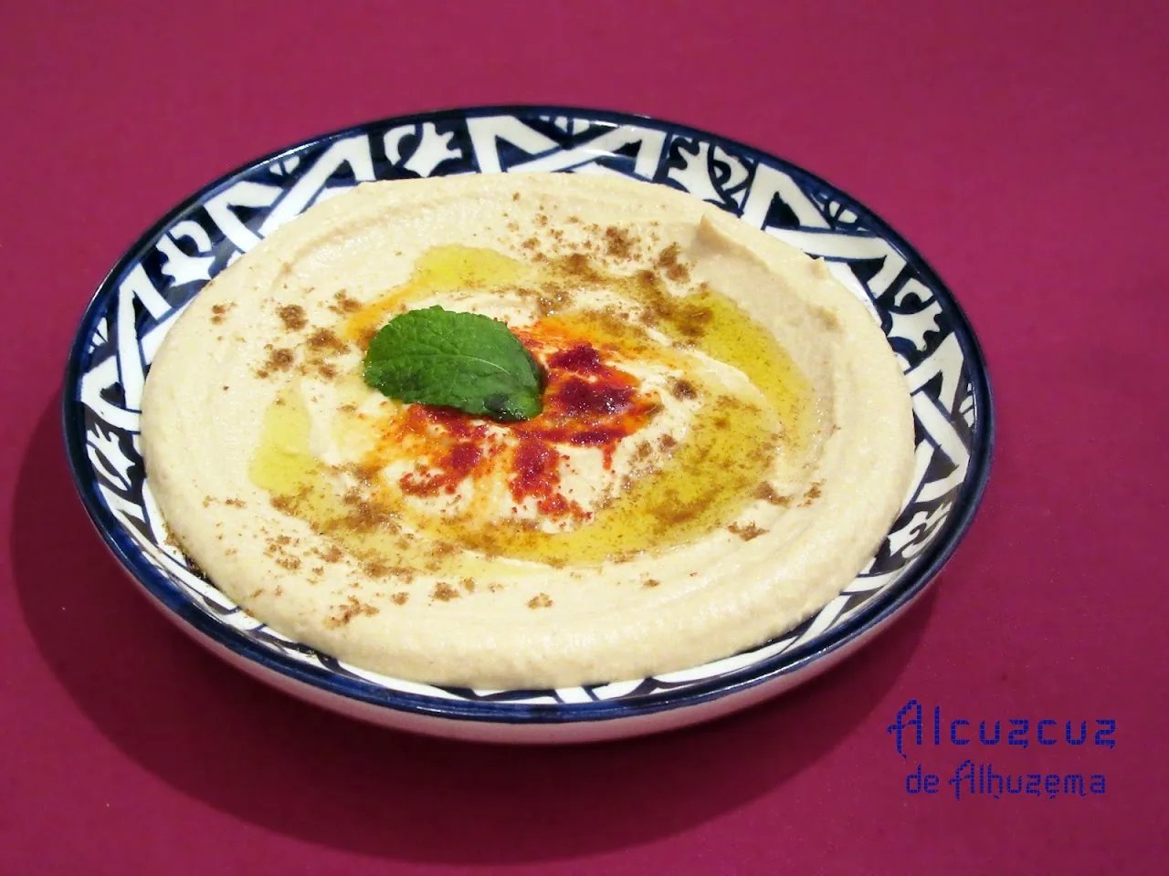 A bowl of hummus drizzled with olive oil and paprika