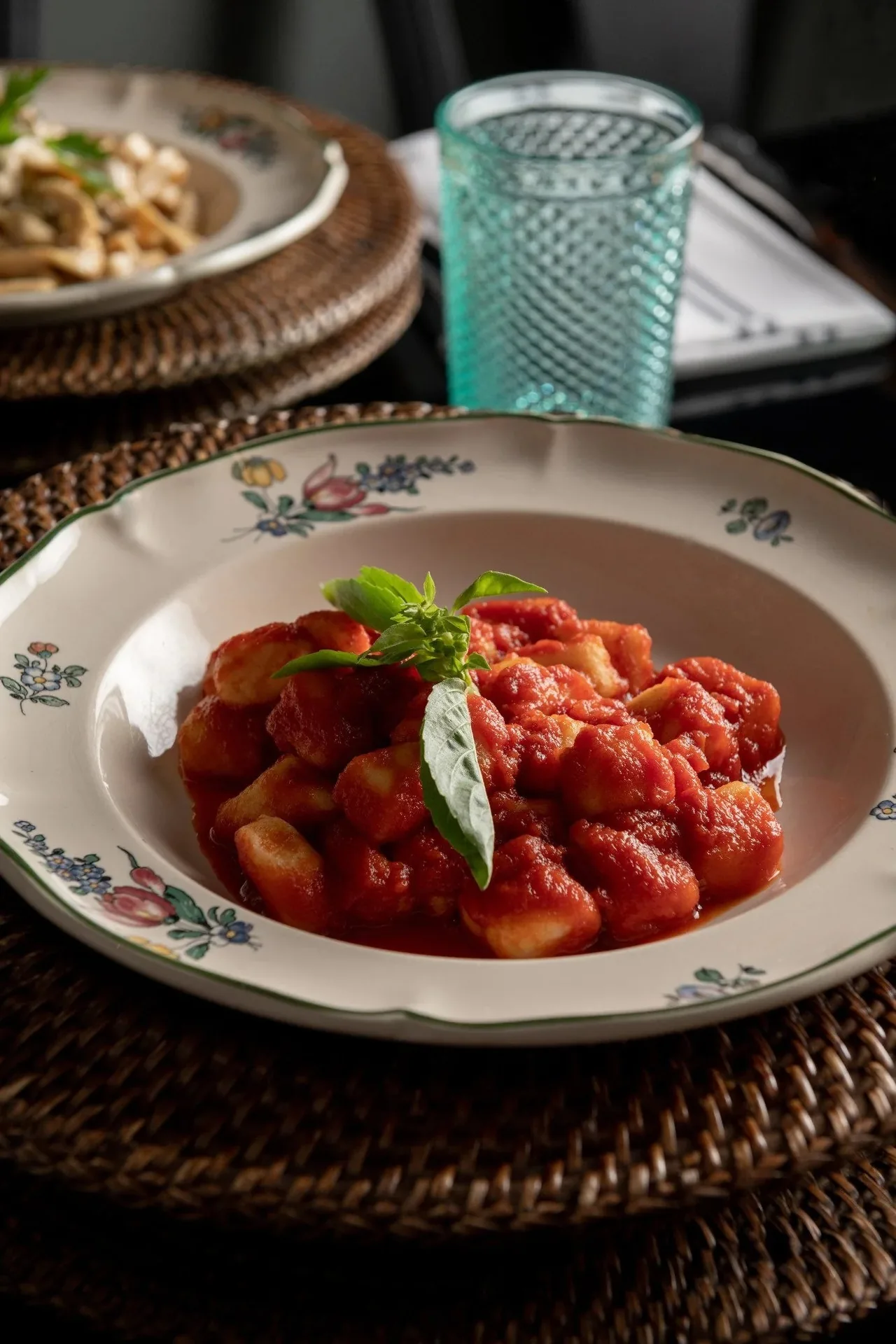 Pasta in tomato sauce with basil in a floral-rimmed bowl