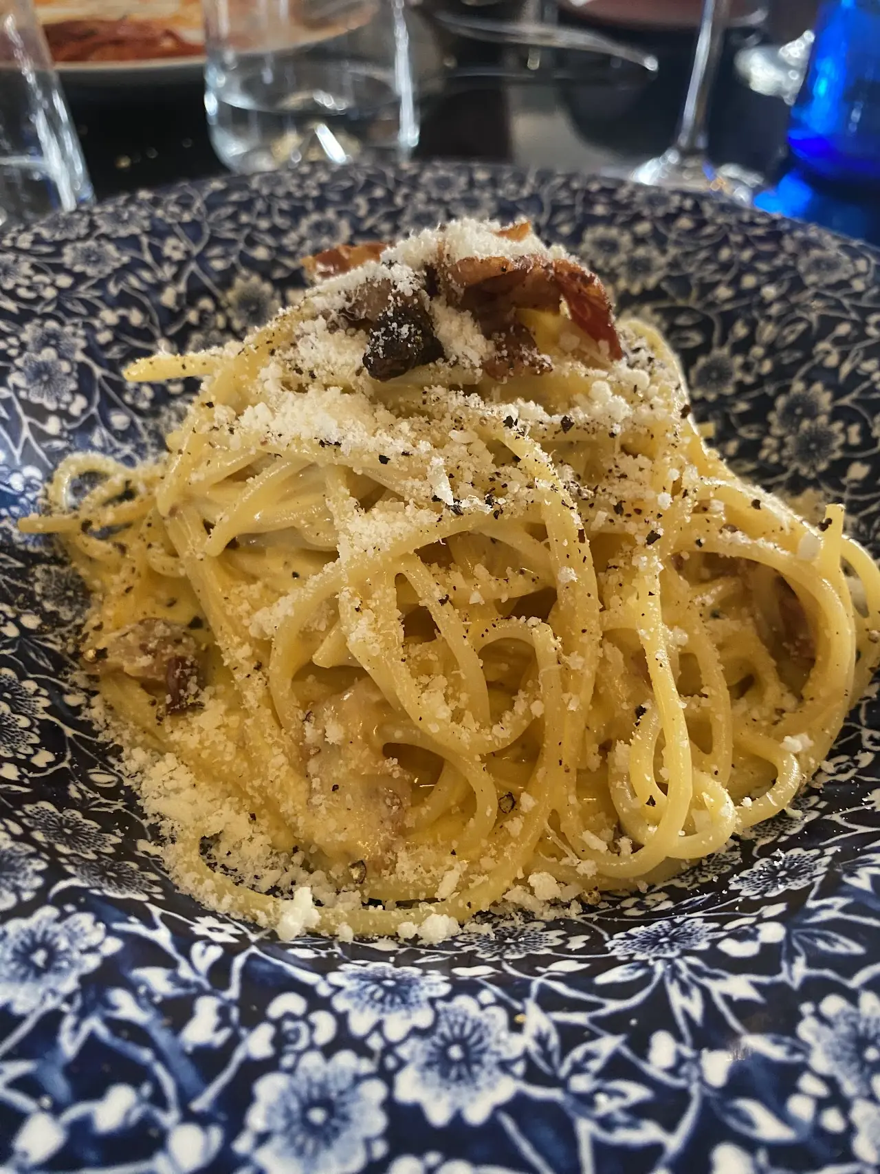 Pasta tossed with mushrooms and grated cheese on a blue-patterned plate.