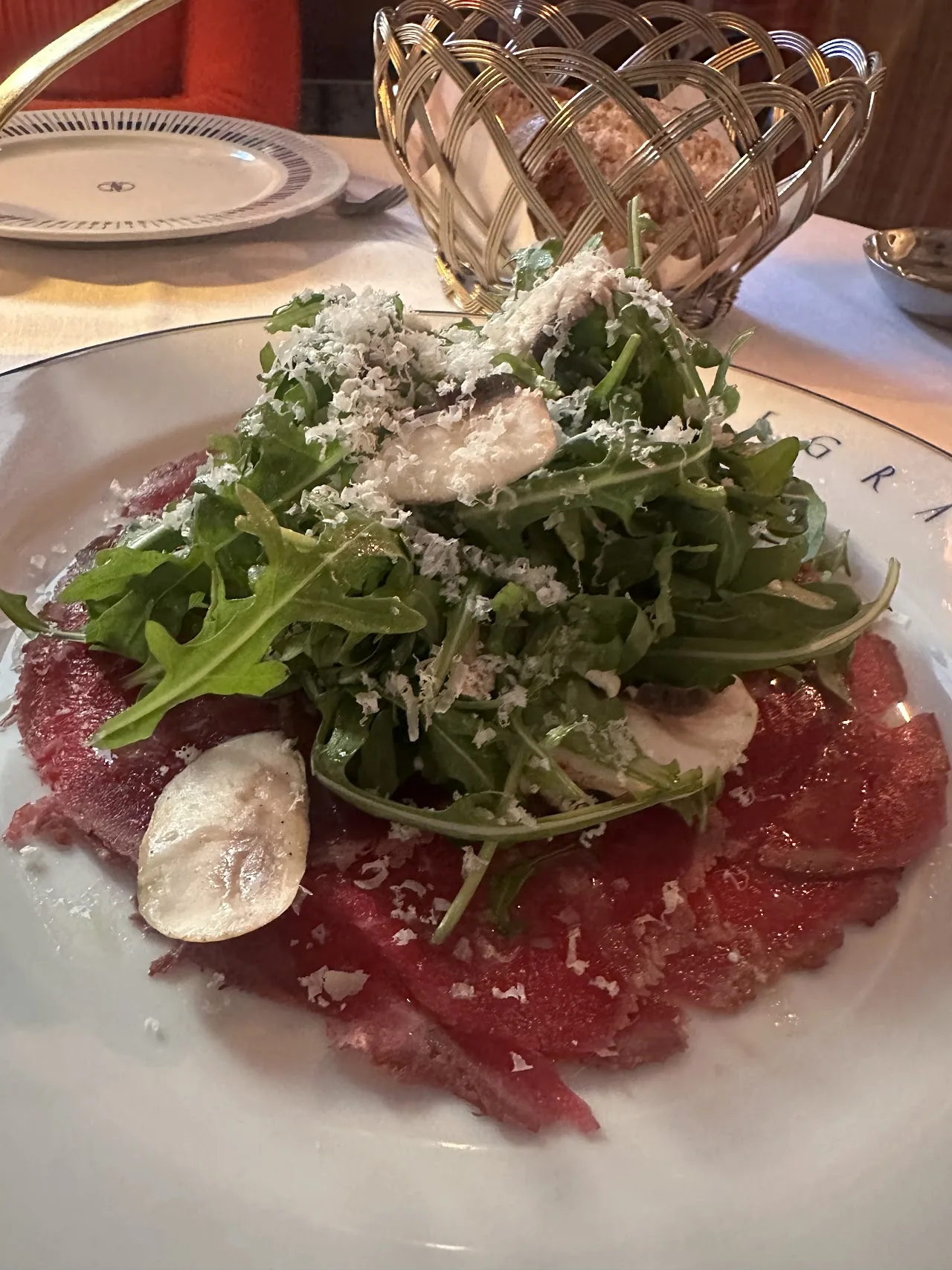 Beef carpaccio topped with arugula and shaved cheese