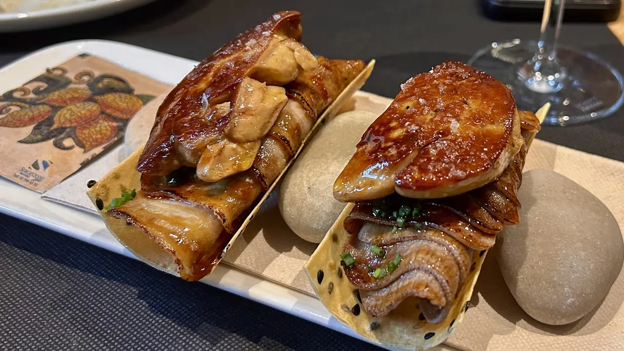 Two open tacos topped with seared foie gras and eel on crispy tortillas