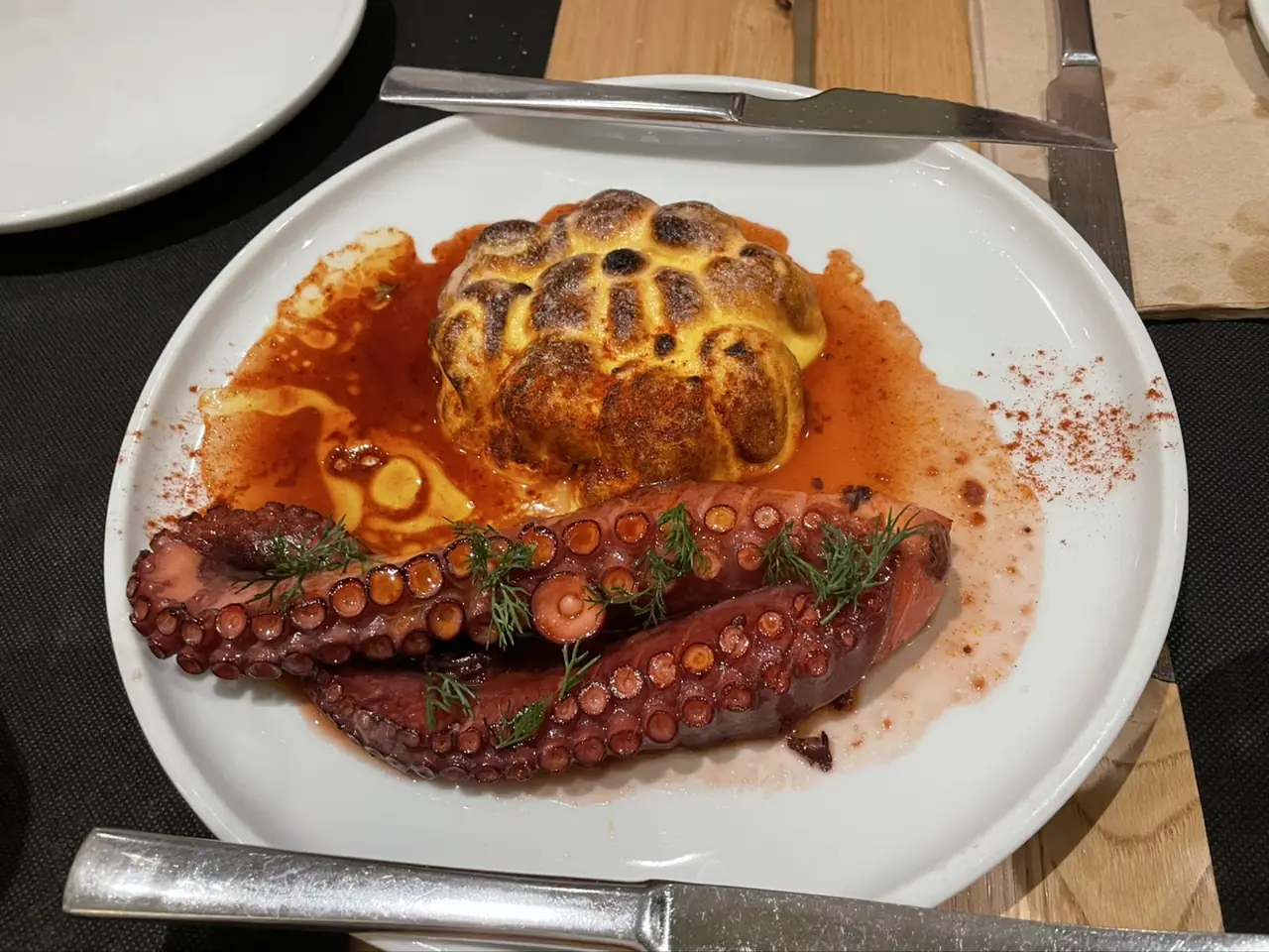 Grilled octopus tentacles with a roasted potato and paprika sauce, garnished with dill