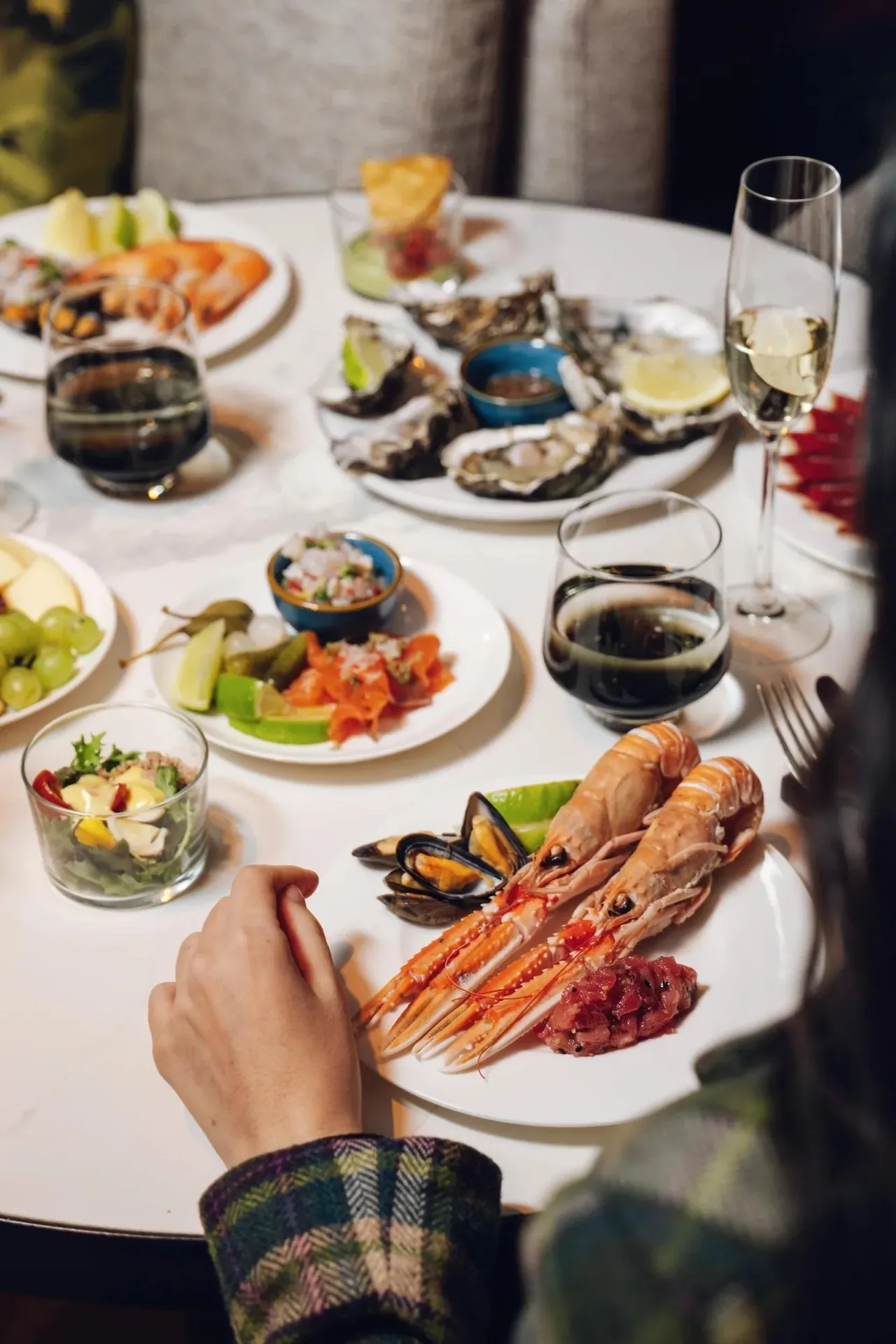 A round white table set with plates of seafood and glasses