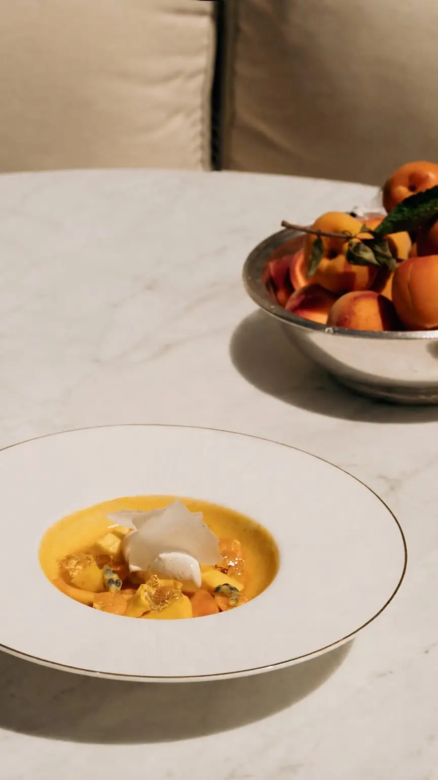 Fruit dessert in citrus sauce with a bowl of whole apricots nearby