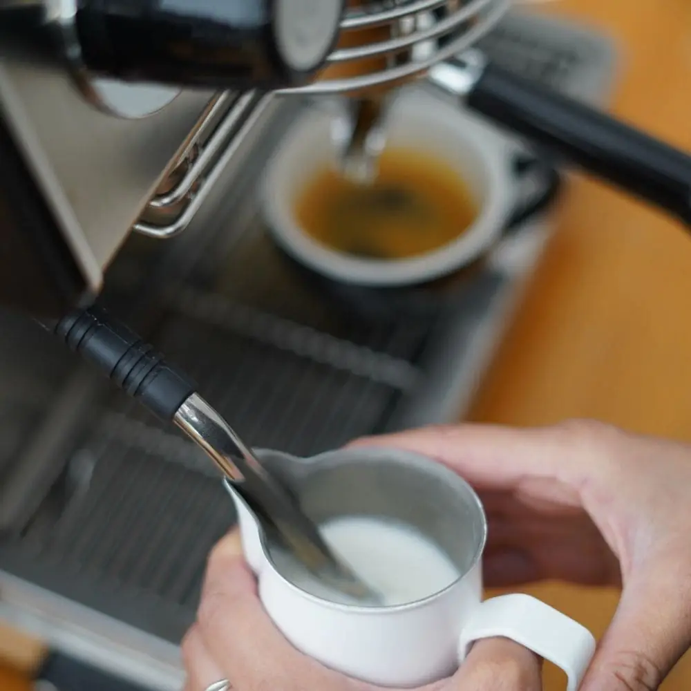 Espresso extracting into a white cup beside a jug of steamed milk on an espresso machine, Animal Coffee Roasters