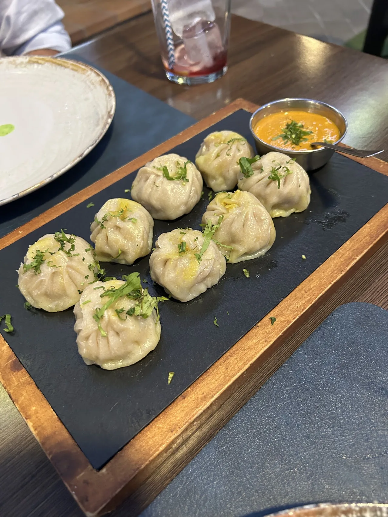 A tray of steamed momo dumplings with dipping sauce