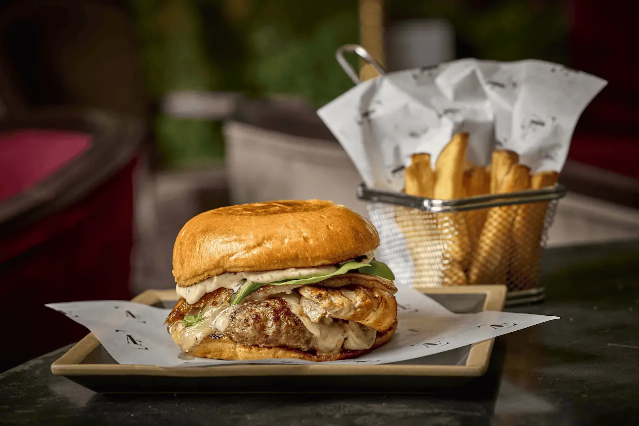 A burger on a brioche bun with a side of fries in a paper-lined basket.