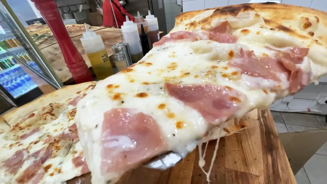 A close-up of a ham and cheese pizza slice