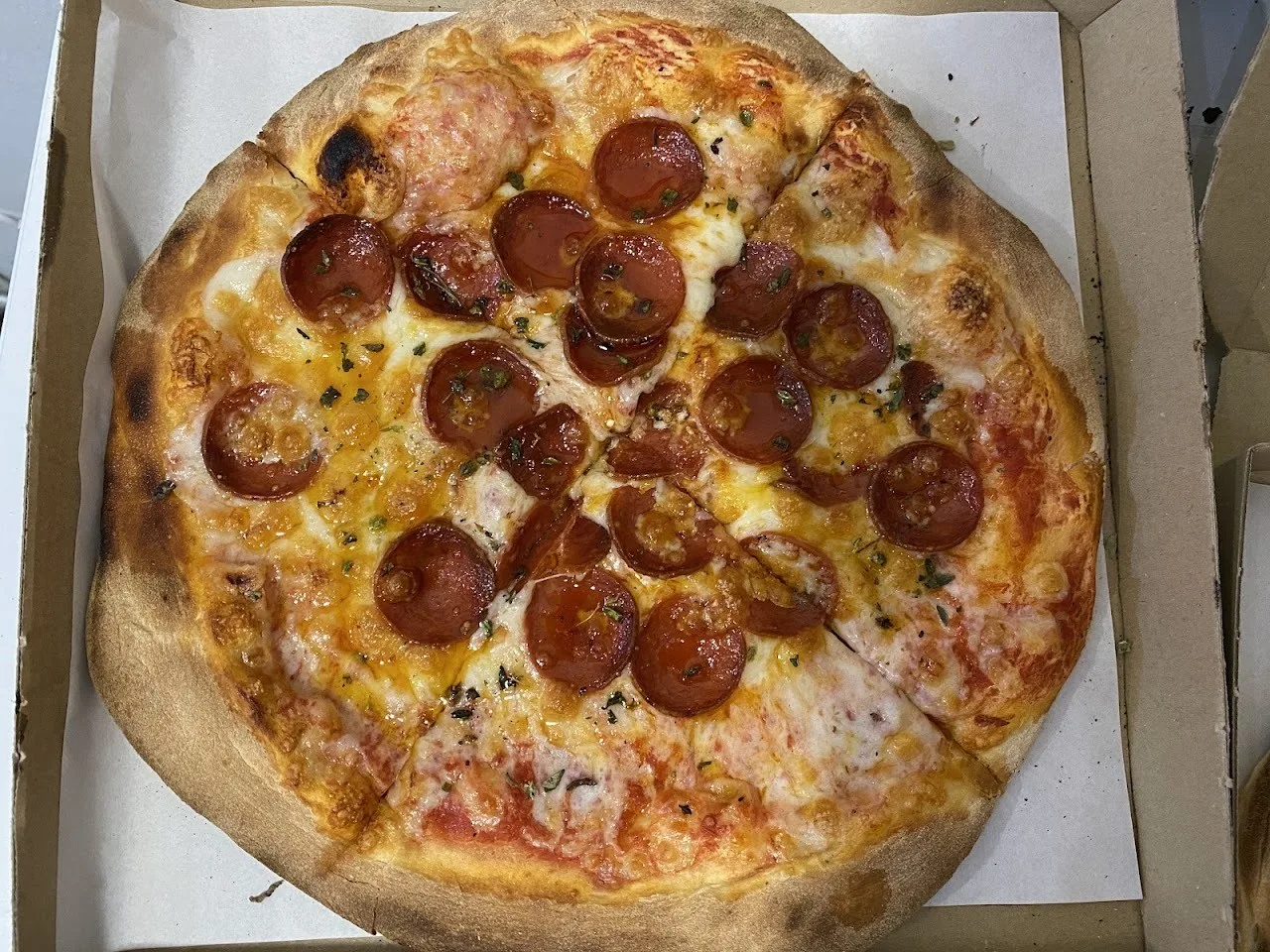 A pepperoni pizza with melted cheese in a cardboard box