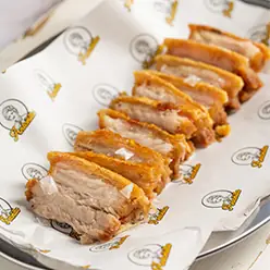Sliced crispy roast pork belly served on branded paper on a tray
