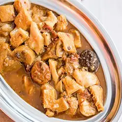 Overhead view of a meat and potato stew served in a metal cazuela