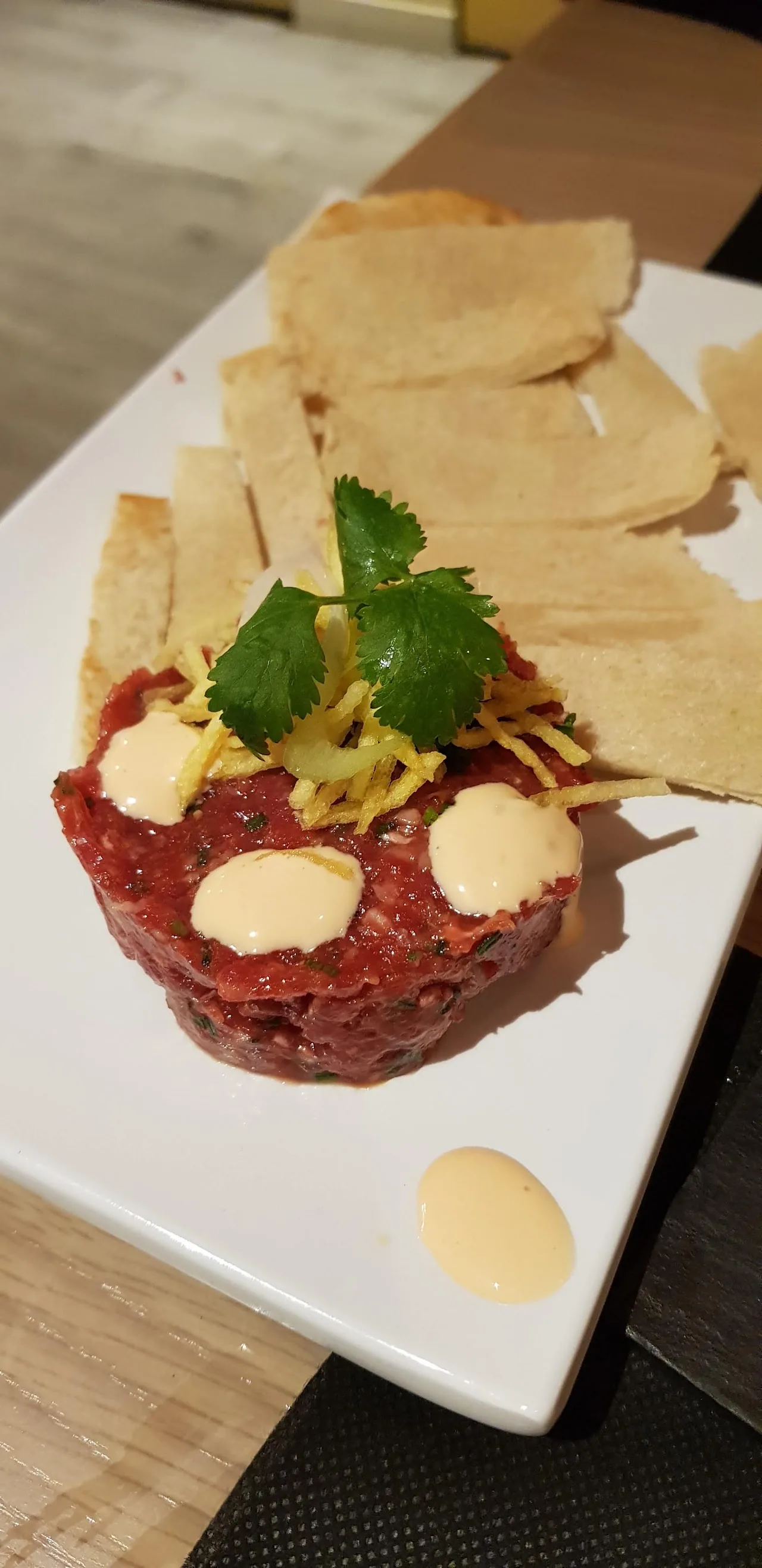 A plated beef tartare with sesame seeds and crispy crackers