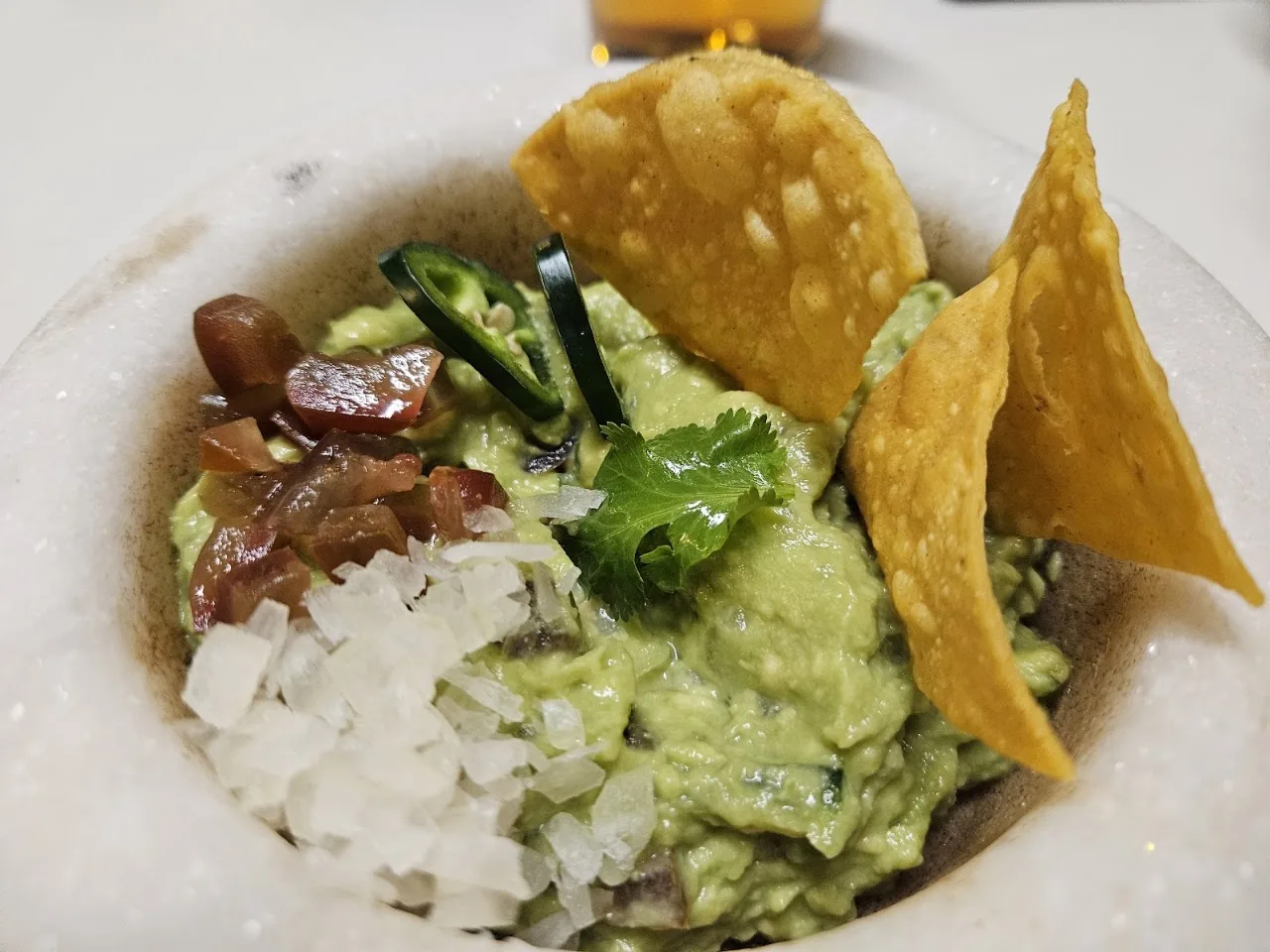 A bowl of guacamole with tortilla chips and diced onion