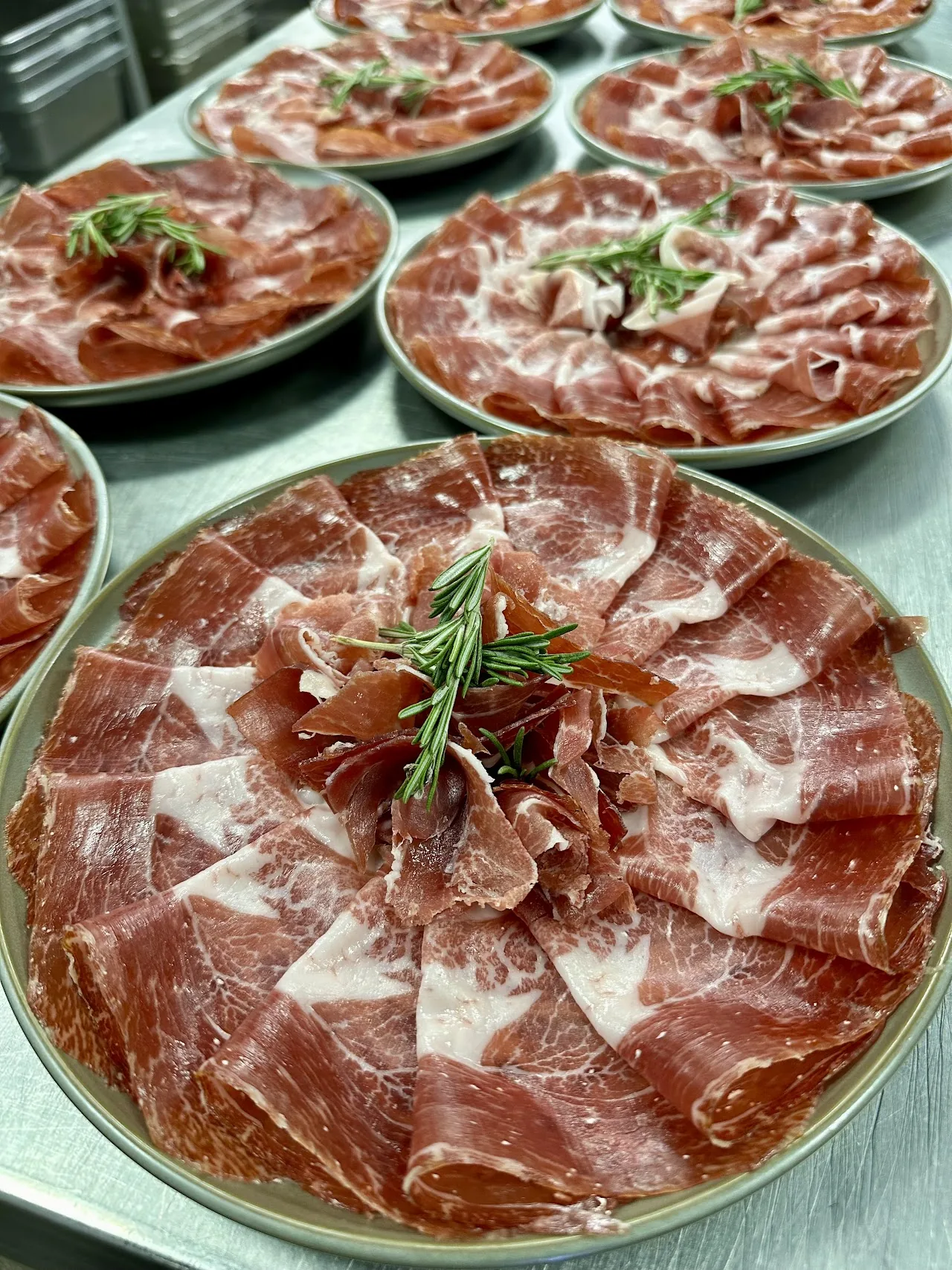 Plates of thinly sliced cured ham garnished with rosemary