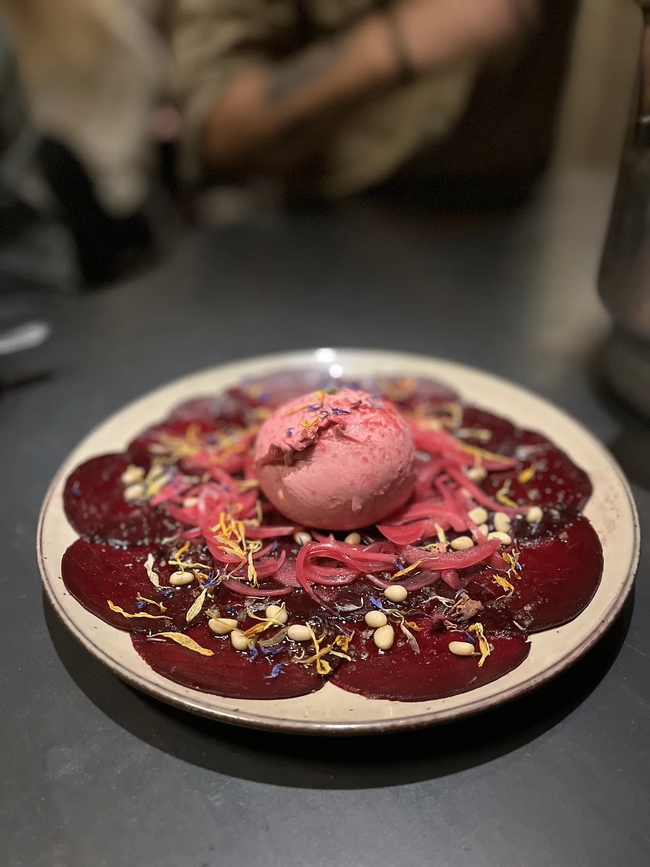 A plate of beet carpaccio topped with a scoop of pink sorbet