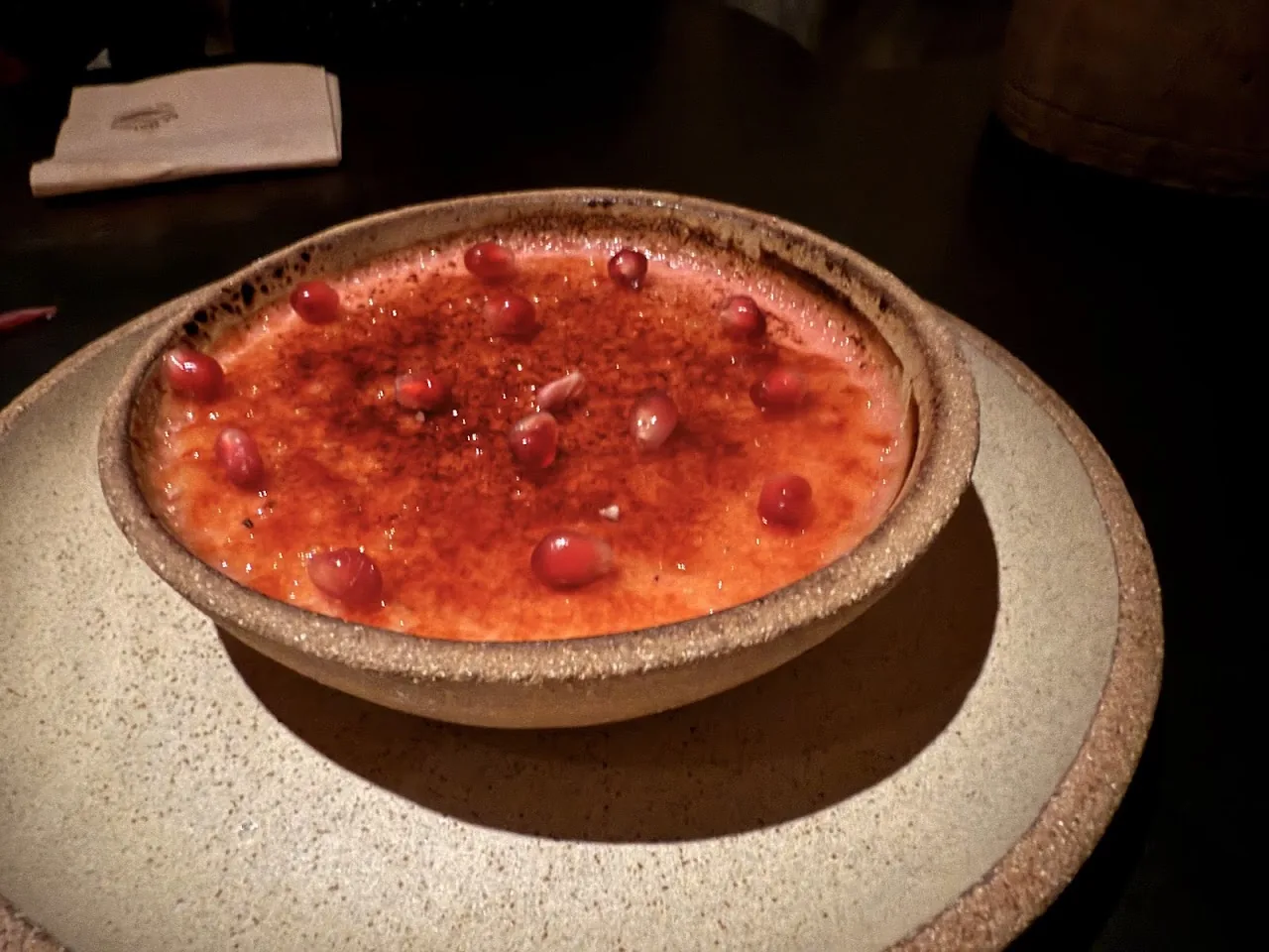A pink cocktail or drink garnished with pomegranate seeds in a stone bowl