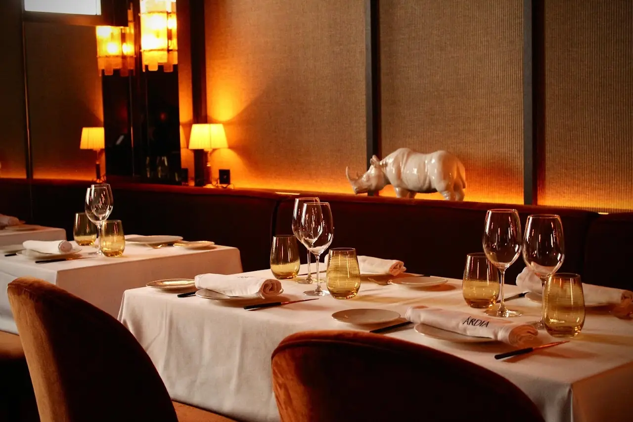 A warmly lit dining room with set tables and upholstered chairs.