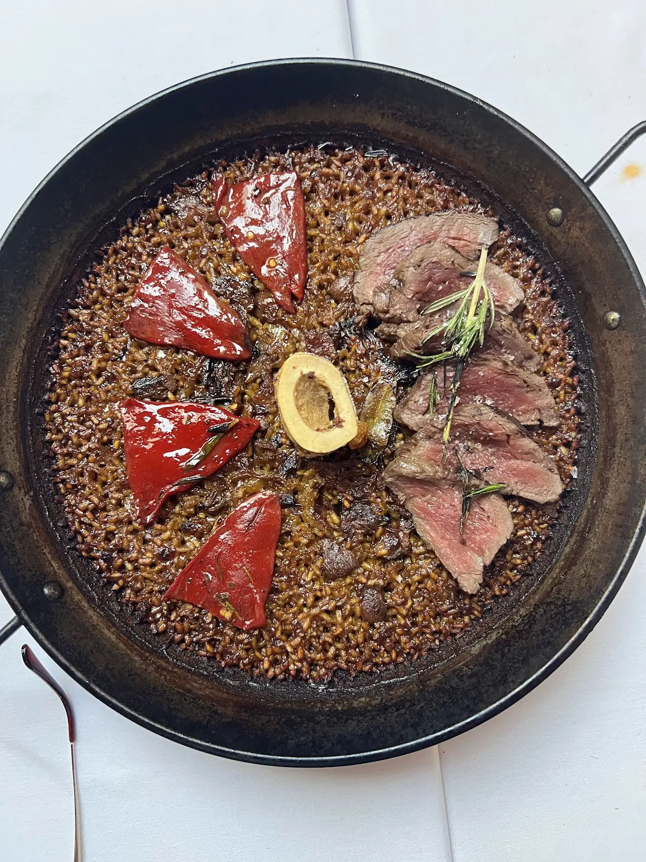 A skillet with grilled meat, shellfish, and grains.