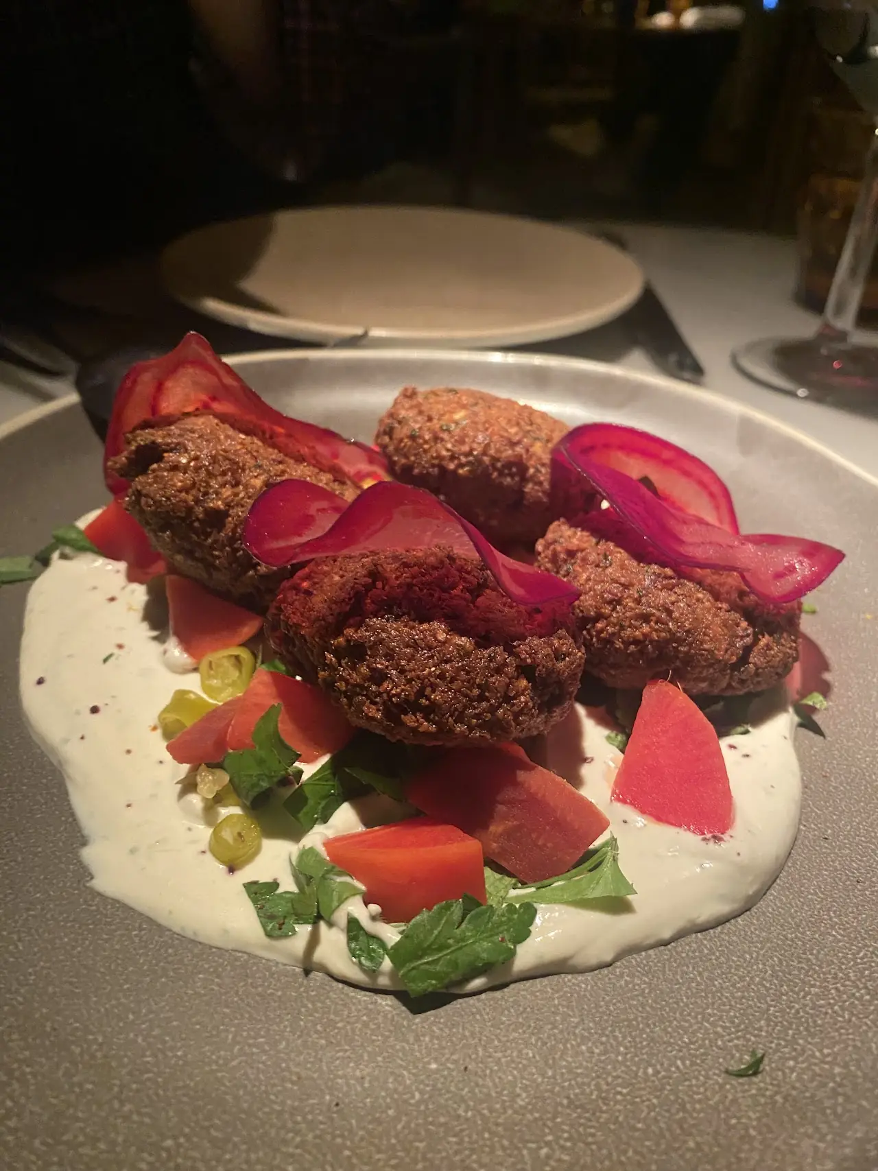 Fried patties with pickled red onion and diced tomato over a white sauce
