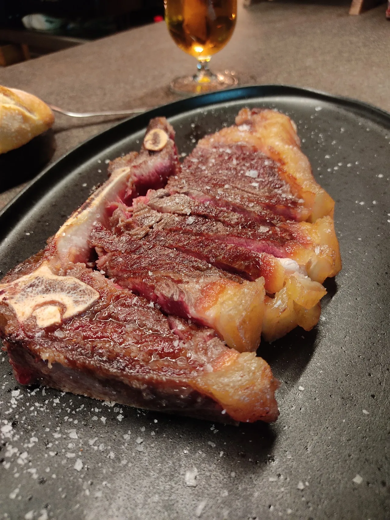 A sliced bone-in steak on a dark plate