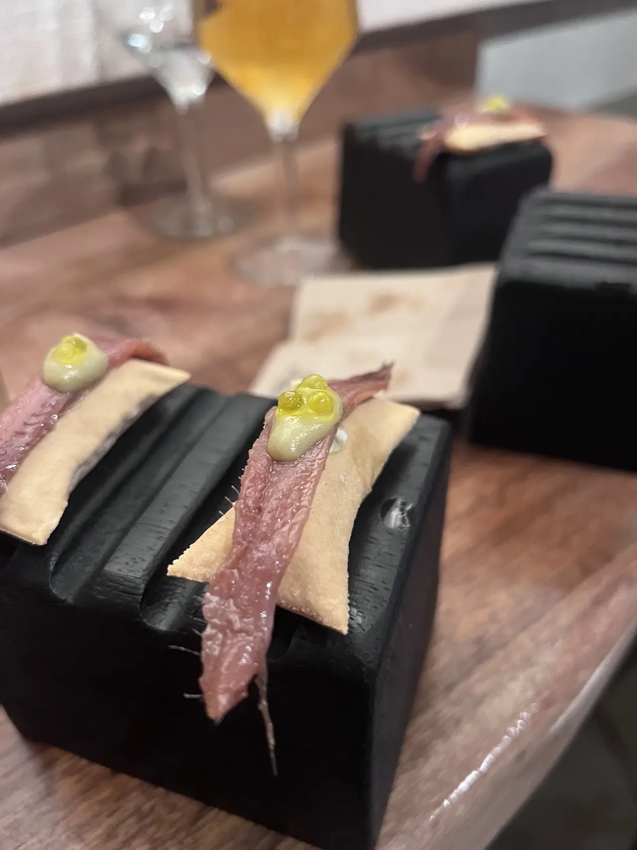 Two bite-size cured fish and cracker canapes on black serving blocks
