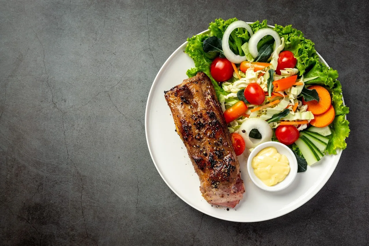 A grilled steak with a mixed salad of tomato, cucumber and onion