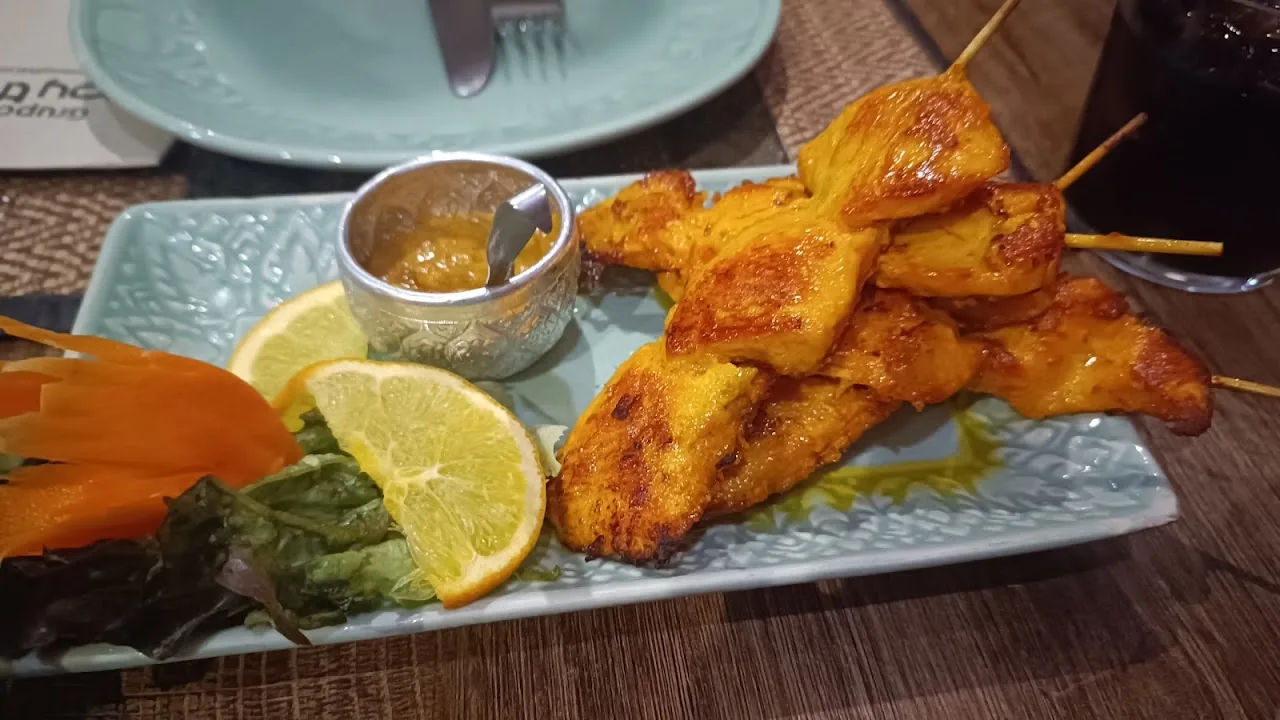 Grilled chicken skewers on a plate with lime and dipping sauce