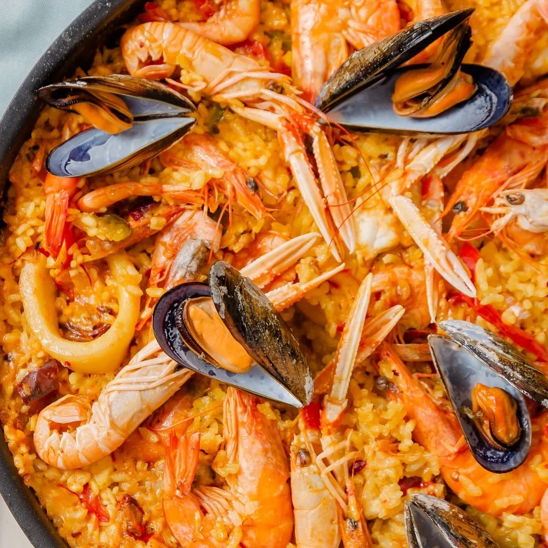 Overhead view of a paella pan with prawns, langoustines, mussels and squid rings on yellow rice