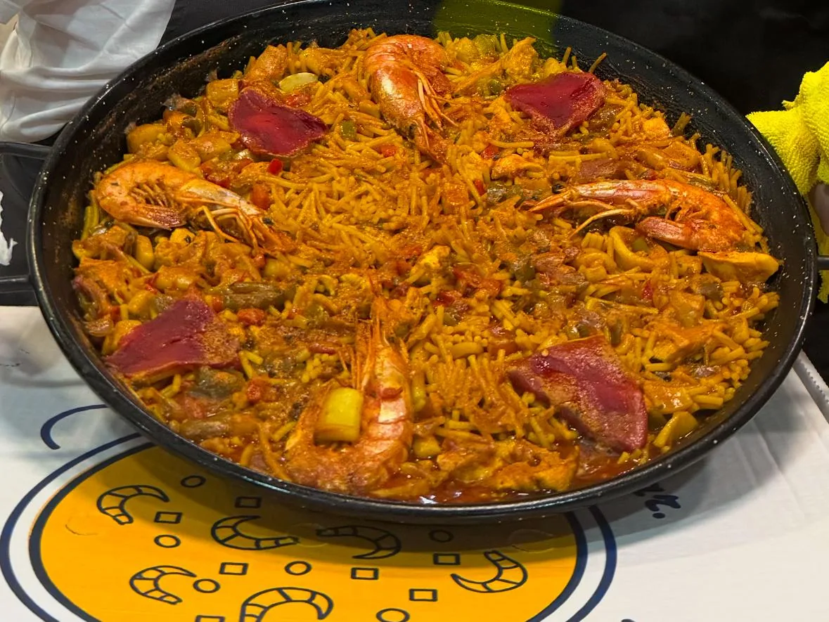 A paella pan filled with saffron rice, shrimp and chorizo