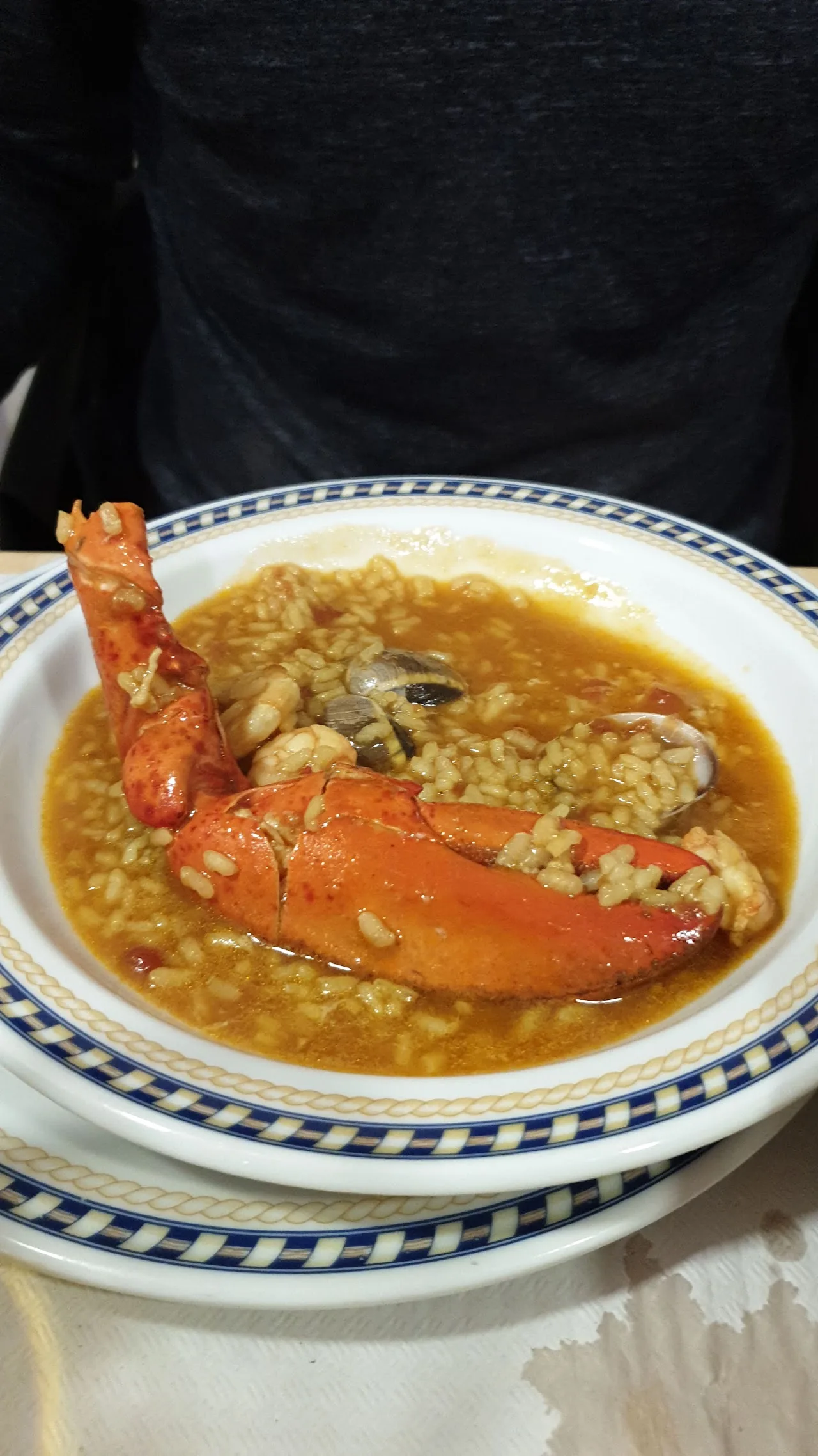 A bowl of rice with a whole crab claw served with bread