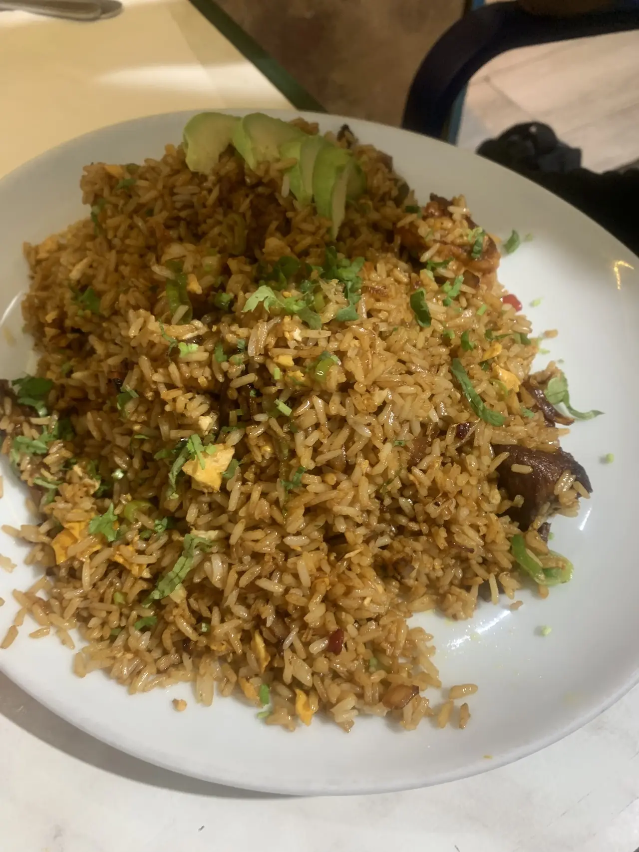 A plate of fried rice with pieces of meat and spring onion