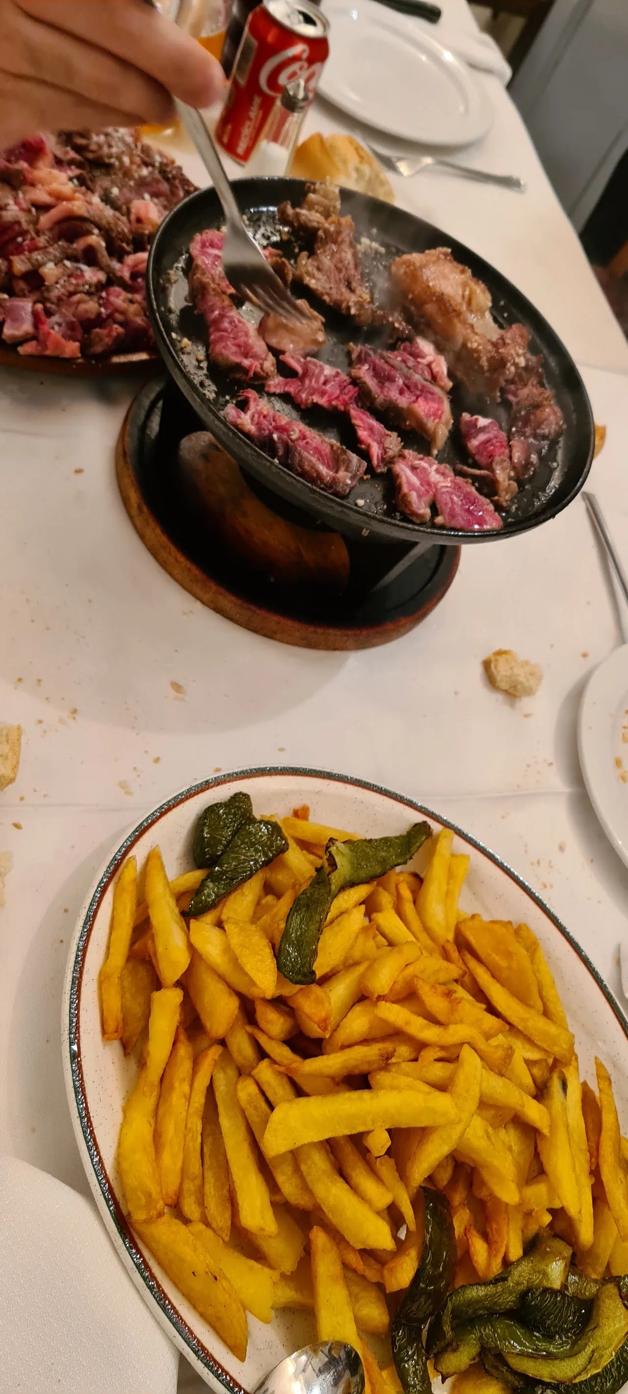 A platter of grilled meat with a side of fried peppers and chips