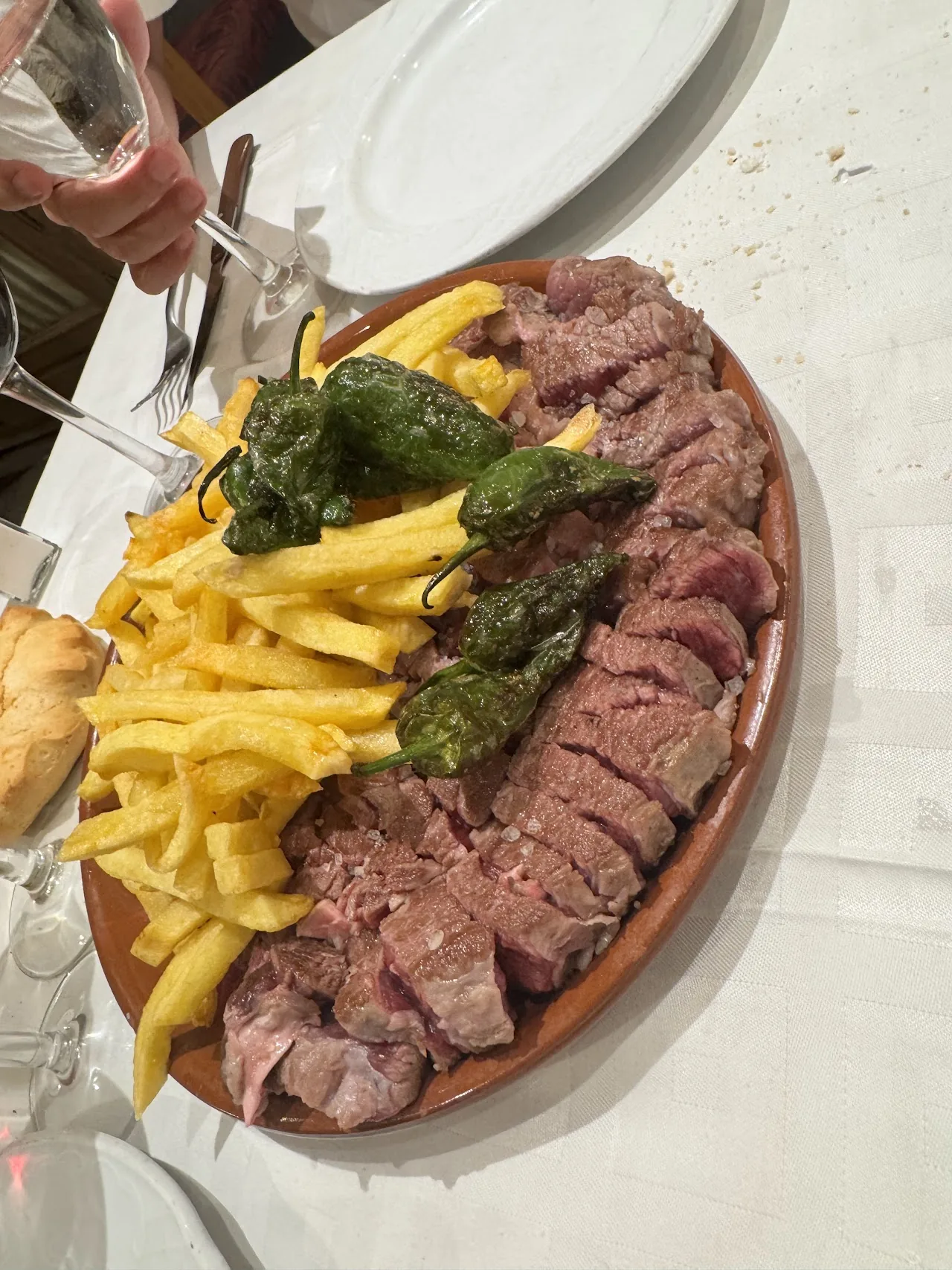 A sliced steak platter with fries and grilled green peppers