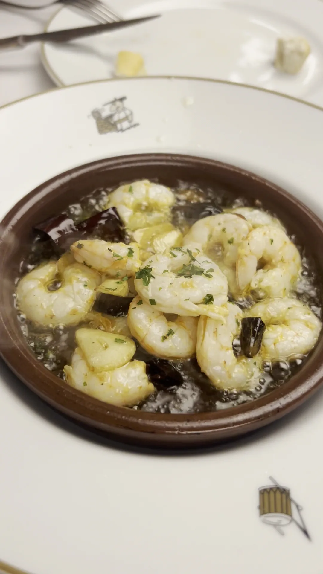 A terracotta dish of prawns cooked in garlic and oil