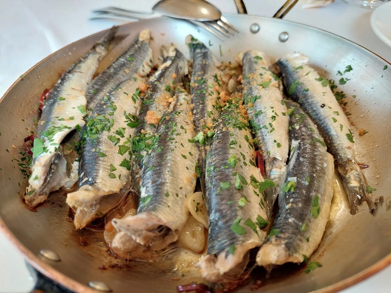 A plate of grilled sardines drizzled with garlic and herb oil